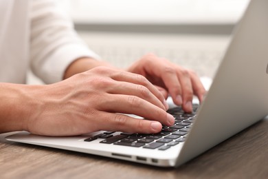 Photo of Copywriter using laptop at wooden table indoors, closeup
