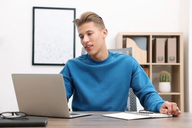 Photo of Copywriter using laptop at wooden table indoors
