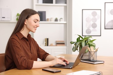 Photo of Copywriter using laptop at wooden table indoors