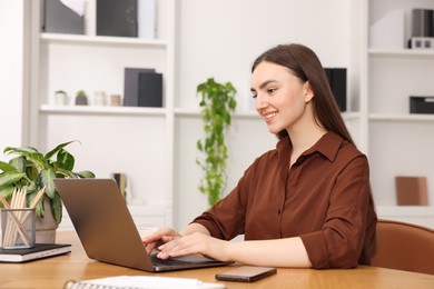 Photo of Copywriter using laptop at wooden table indoors