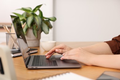 Photo of Copywriter using laptop at wooden table indoors, closeup