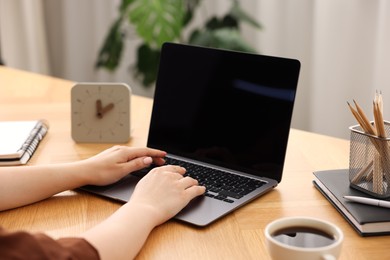 Photo of Copywriter using laptop at wooden table indoors, closeup