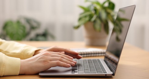 Photo of Copywriter using laptop at wooden table indoors, closeup
