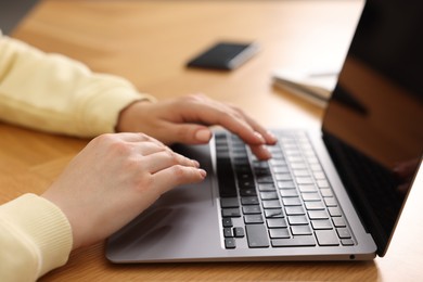 Photo of Copywriter using laptop at wooden table indoors, closeup