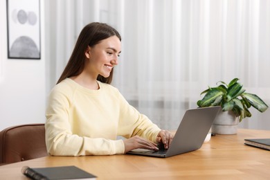 Photo of Copywriter using laptop at wooden table indoors