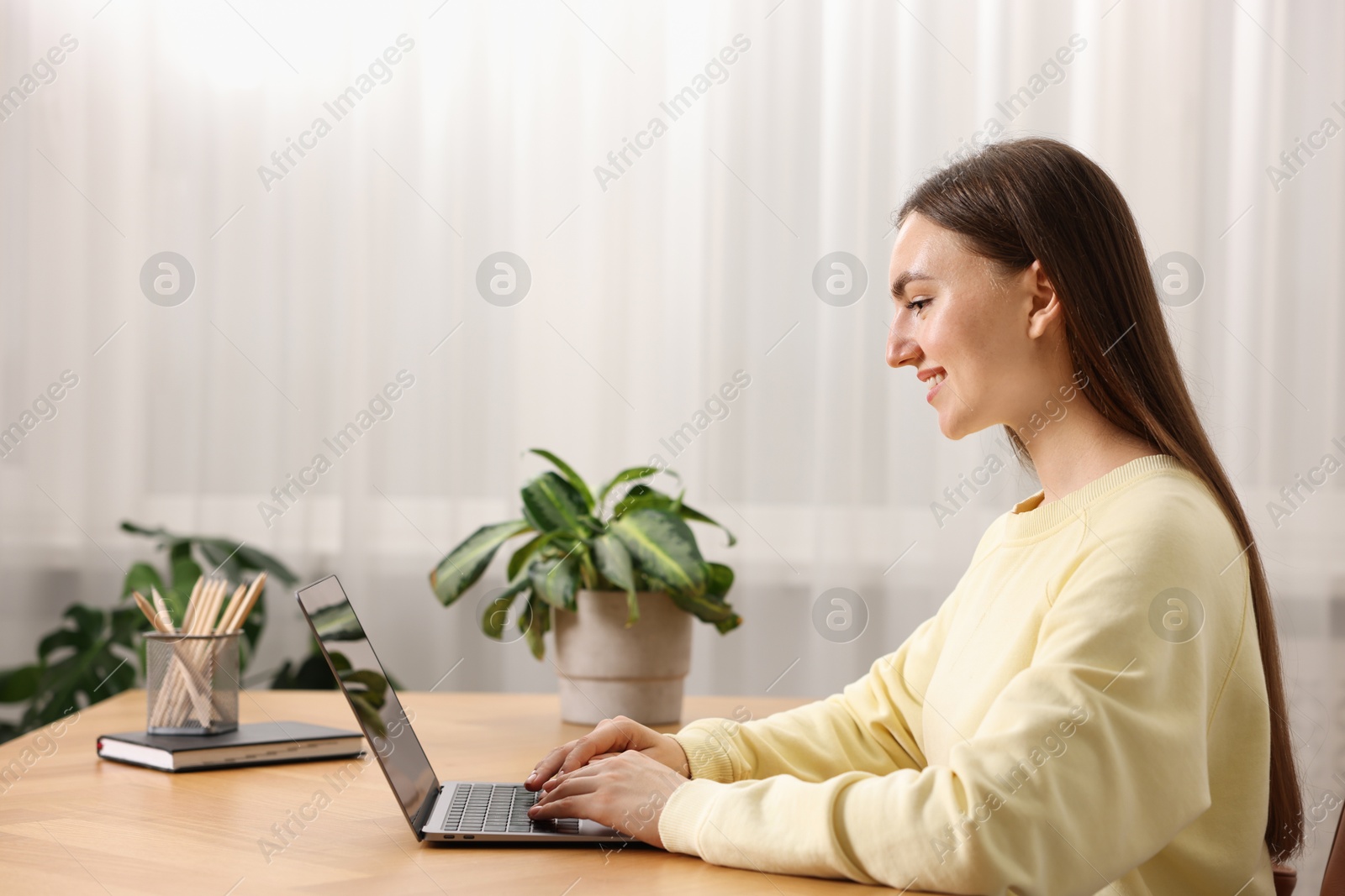 Photo of Copywriter using laptop at wooden table indoors