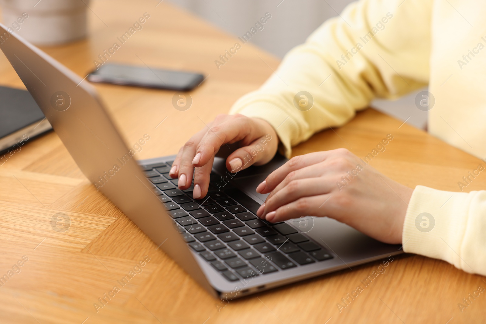 Photo of Copywriter using laptop at wooden table indoors, closeup