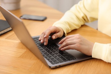 Photo of Copywriter using laptop at wooden table indoors, closeup