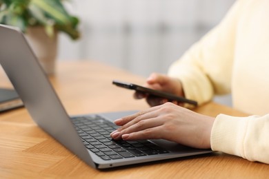 Photo of Copywriter using laptop at wooden table indoors, closeup