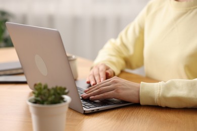 Photo of Copywriter using laptop at wooden table indoors, closeup
