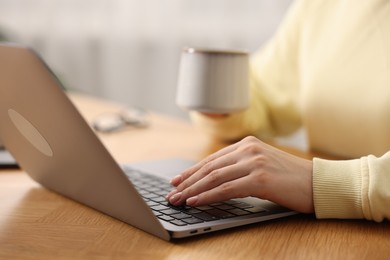 Photo of Copywriter using laptop at wooden table indoors, closeup