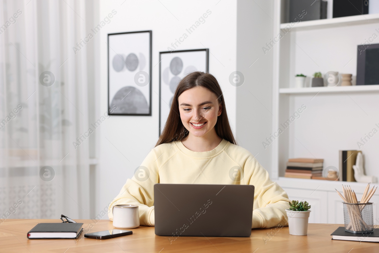 Photo of Copywriter using laptop at wooden table indoors