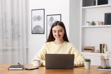 Photo of Copywriter using laptop at wooden table indoors