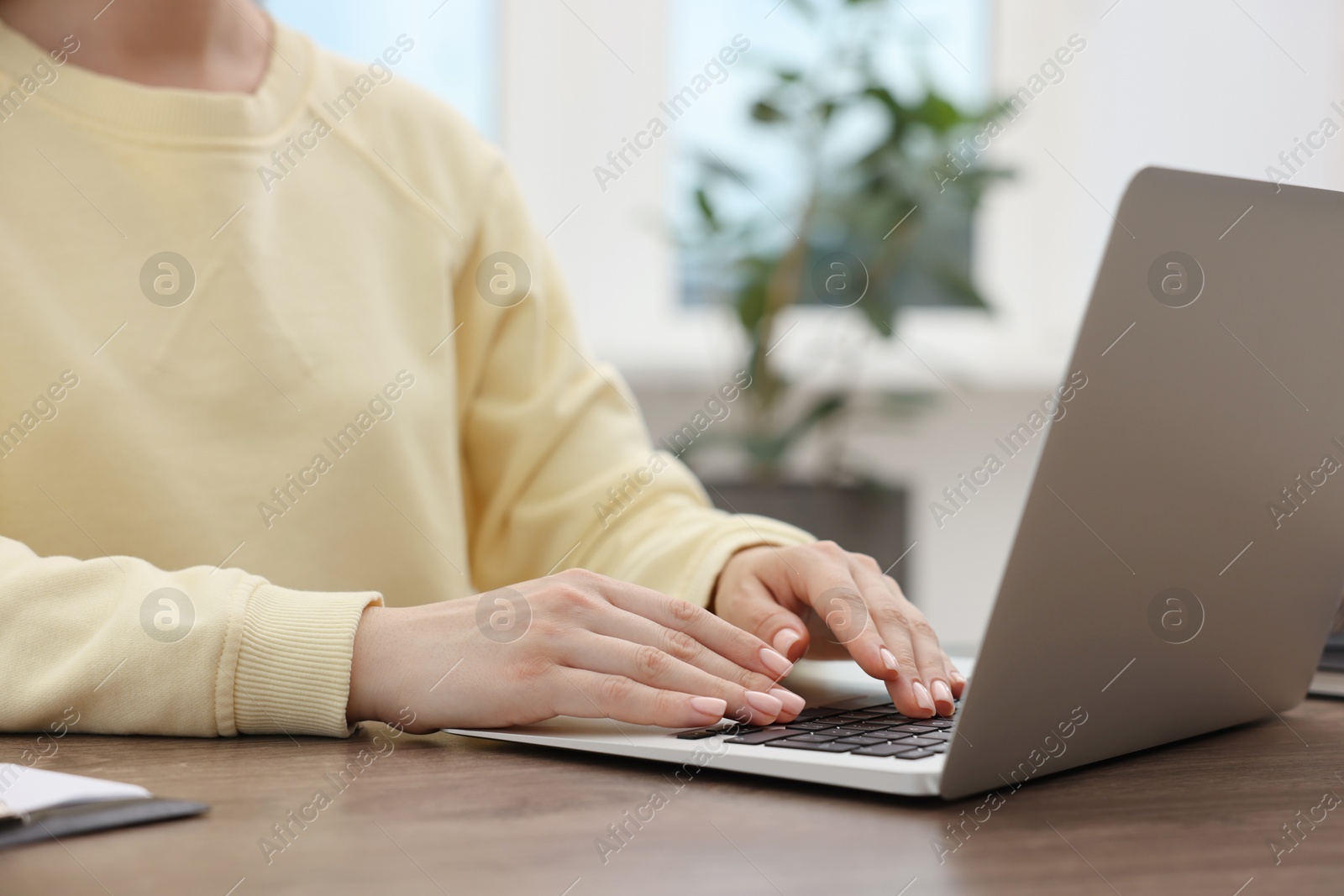 Photo of Copywriter using laptop at wooden table indoors, closeup