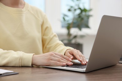 Photo of Copywriter using laptop at wooden table indoors, closeup