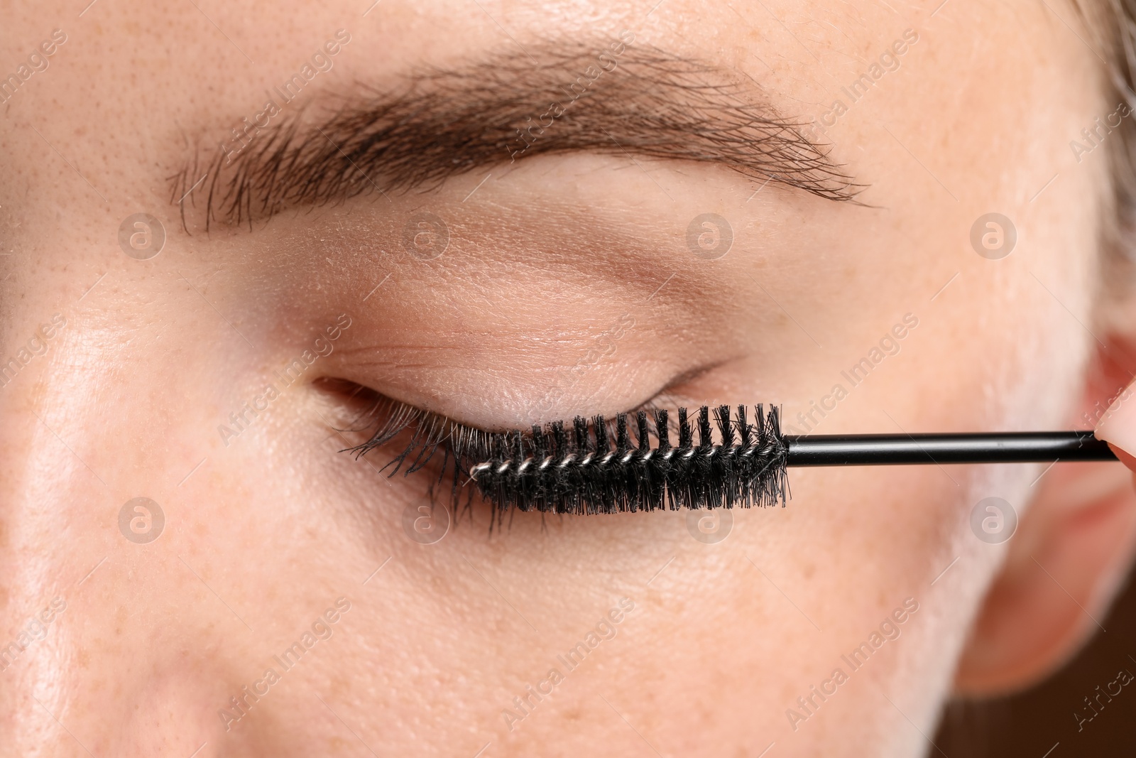 Young woman applying mascara onto her eyelashes, closeup Photo of Young woman applying mascara onto her eyelashes, closeup