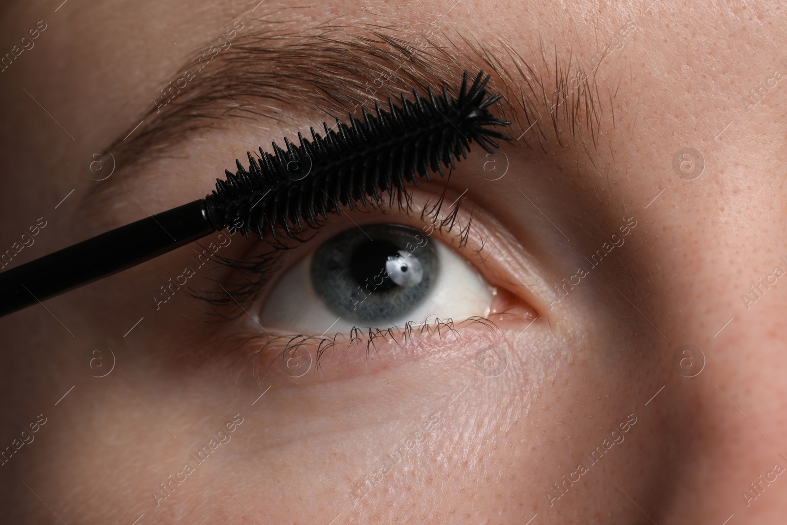 Young woman applying mascara onto her eyelashes, closeup Photo of Young woman applying mascara onto her eyelashes, closeup