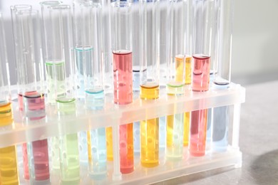 Photo of Test tubes with different samples on grey table in laboratory, closeup. Solution chemistry