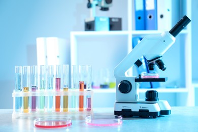 Photo of Petri dishes with different samples, test tubes and microscope on table in laboratory. Solution chemistry