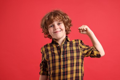 Photo of Strength. Happy little boy showing his biceps on red background
