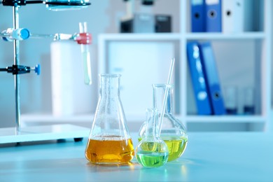 Photo of Laboratory glassware with different samples on table indoors. Solution chemistry