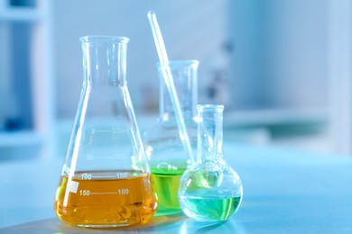 Photo of Solution chemistry. Laboratory glassware with different samples on table indoors, closeup. Space for text