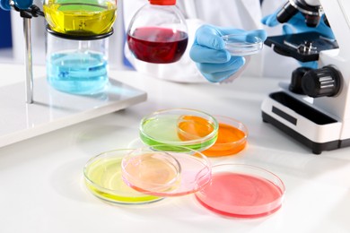 Photo of Scientist working with different samples at white table in laboratory, closeup. Solution chemistry