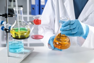 Photo of Scientist working with different samples at white table in laboratory, closeup. Solution chemistry