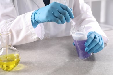 Photo of Scientist working with sample at grey table in laboratory, closeup. Solution chemistry