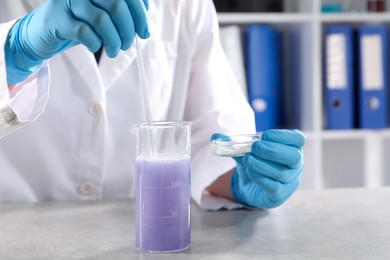 Photo of Scientist working with sample at grey table in laboratory, closeup. Solution chemistry