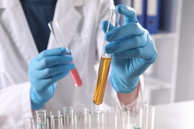 Photo of Scientist with test tubes of different samples in laboratory, closeup. Solution chemistry