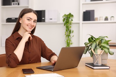 Photo of Copywriter using laptop at wooden table indoors