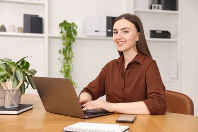 Photo of Copywriter using laptop at wooden table indoors