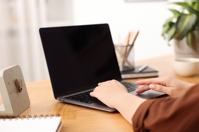 Photo of Copywriter using laptop at wooden table indoors, closeup