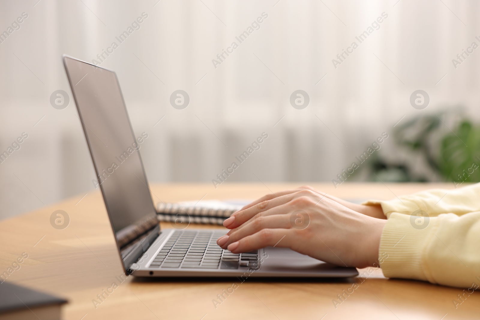 Photo of Copywriter using laptop at wooden table indoors, closeup