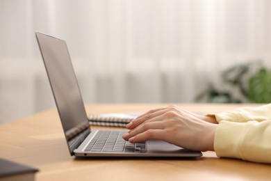 Photo of Copywriter using laptop at wooden table indoors, closeup