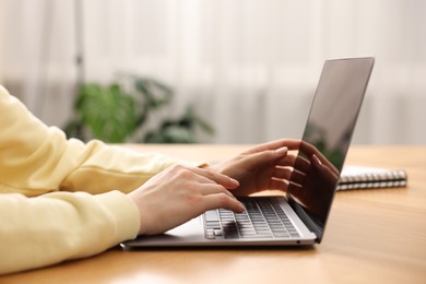 Photo of Copywriter using laptop at wooden table indoors, closeup
