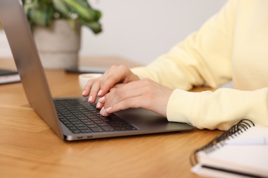 Photo of Copywriter using laptop at wooden table indoors, closeup