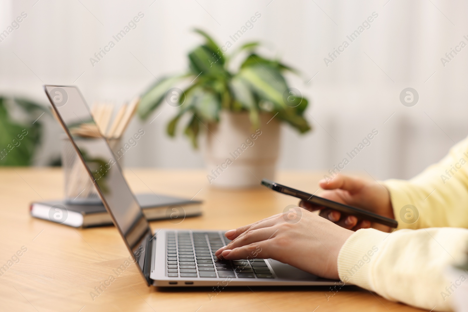 Photo of Copywriter using laptop at wooden table indoors, closeup