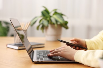 Photo of Copywriter using laptop at wooden table indoors, closeup