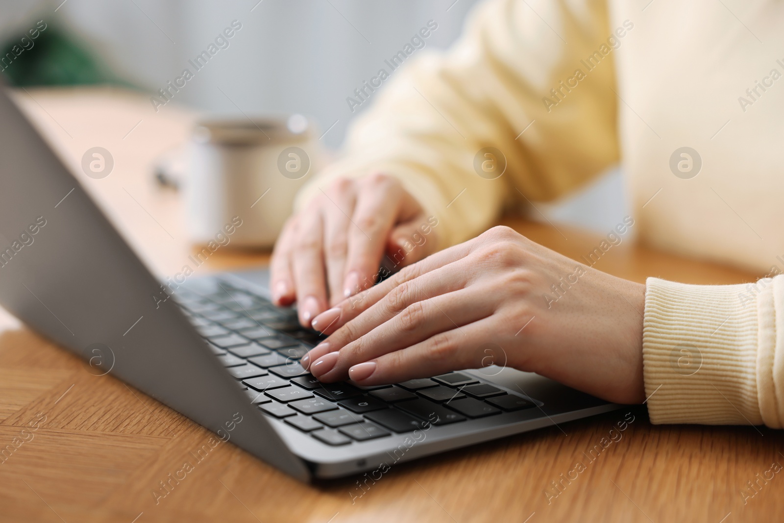 Photo of Copywriter using laptop at wooden table indoors, closeup