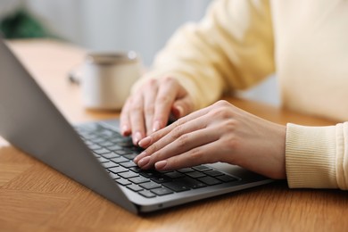 Photo of Copywriter using laptop at wooden table indoors, closeup