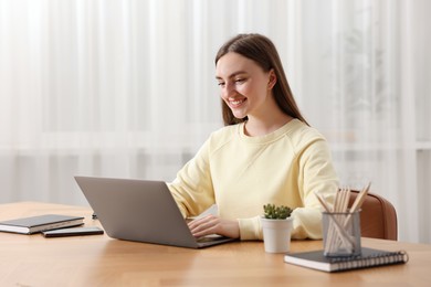 Photo of Copywriter using laptop at wooden table indoors