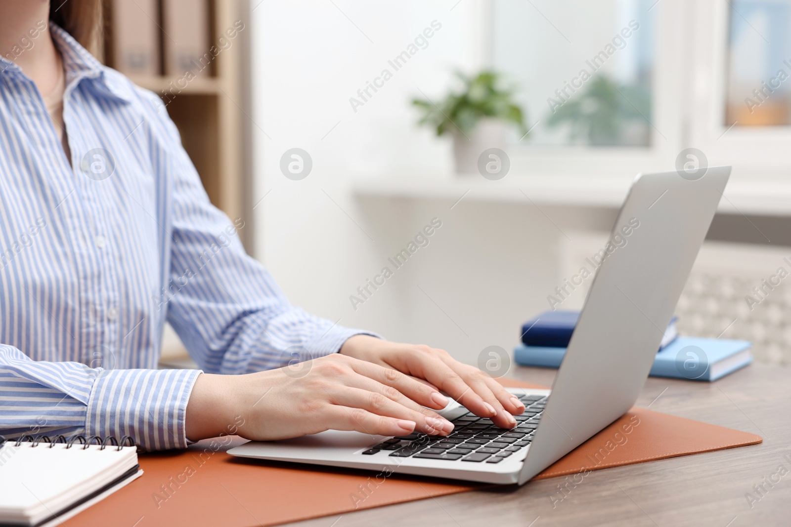 Photo of Copywriter using laptop at wooden table indoors, closeup