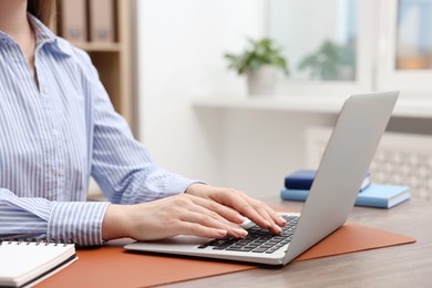 Photo of Copywriter using laptop at wooden table indoors, closeup