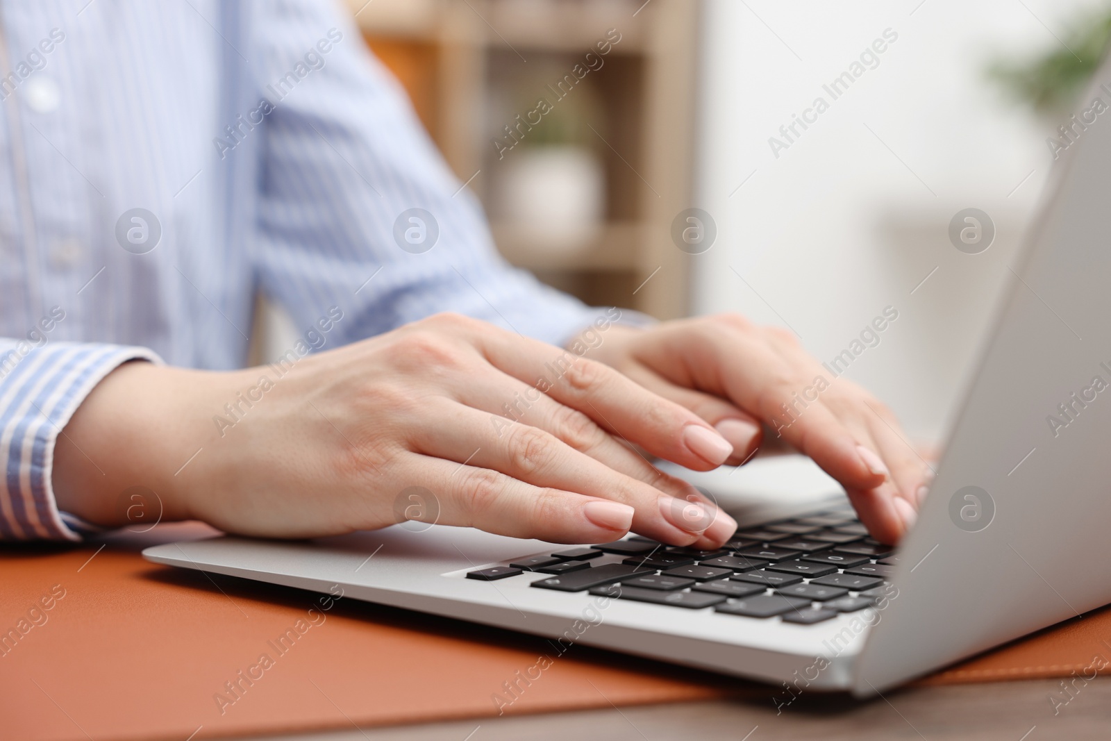 Photo of Copywriter using laptop at wooden table indoors, closeup