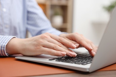 Photo of Copywriter using laptop at wooden table indoors, closeup