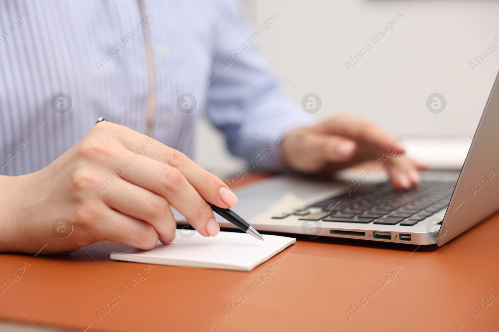 Copywriter using laptop and writing in notebook at table indoors, closeup Photo of Copywriter using laptop and writing in notebook at table indoors, closeup
