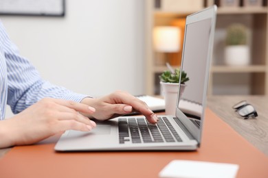 Photo of Copywriter using laptop at table indoors, closeup