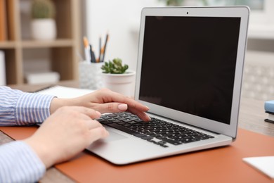Photo of Copywriter using laptop at table indoors, closeup